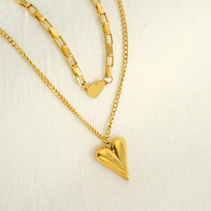 Gros plan du collier double épaisseur doré avec pendentifs cœur et chaîne box
