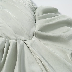 Detailaufnahme aus salbeigrünem Satin mit eleganter Faltenstruktur und Faltenwurf