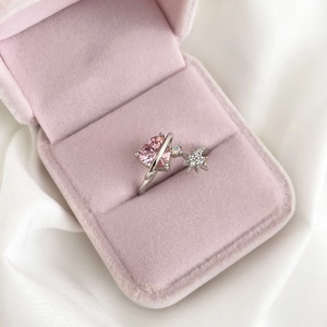 Detail of a pink heart-shaped crystal ring with star accents in a velvet box