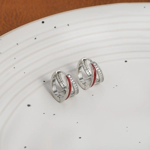 Macro detail of silver earrings with micro-set zircon stones and red enamel inlay