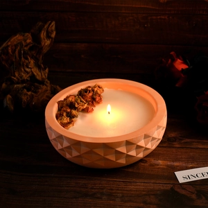 Detail of diamond textured candle bowl with dried flowers in a warm wooden setting
