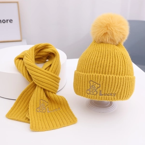 Gelbes Strickset für Kinder mit Bären-Stickerei und flauschigem Pompon in Nahaufnahme
