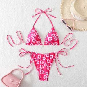 Pink hibiscus floral bikini set with halter top and side tie bottoms on plush background