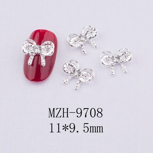 Bijoux à ongles nœud argenté avec strass sur ongle rouge et fond texturé blanc