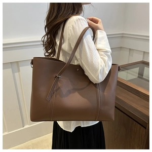 Detail showing high-capacity brown leather tote bag with slim shoulder strap on model