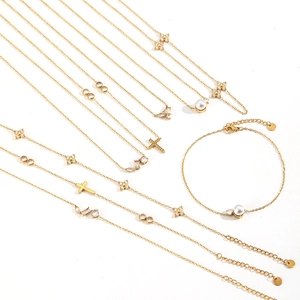 Gold stainless steel jewelry set with cross and clover pendants on white background
