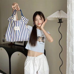 Detail of yellow and blue striped canvas tote bag with woven handles in a modern home setting