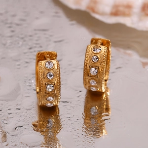 Detailed macro view of gold-plated twisted hoop earrings with sparkling rhinestones