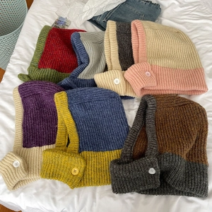 Detail of multi-colored knitted balaclava hats with buttons in thick yarn finish