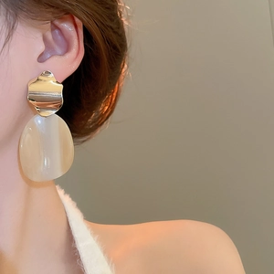 Detail of irregular gold metallic earrings with semi-transparent oval resin pendants
