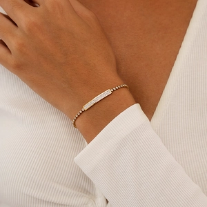 Close-up of gold-plated bracelet with a long bar centerpiece encrusted with zircons