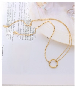 Detail of double-layer gold chain necklace with minimalist round pendant on art book