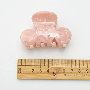 Acetate shark hair claw clip in pink marble finish shown with a ruler for size reference