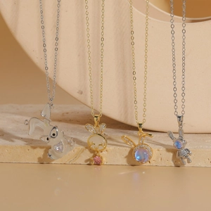 Luxury rabbit zircon pendants on gold and silver necklaces displayed on beige stone