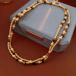 Close-up of double-layered faux tiger eye and pearl necklace on a velvet jewelry box