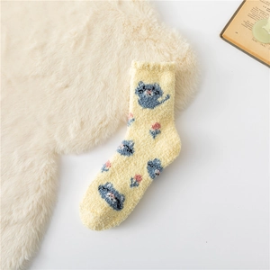 Close-up of fluffy yellow coral fleece sock with cute blue cat and pink flower patterns
