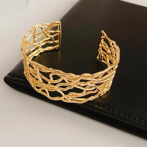 Vue détaillée du bracelet ajouré plaqué or exposé sur un support en cuir noir