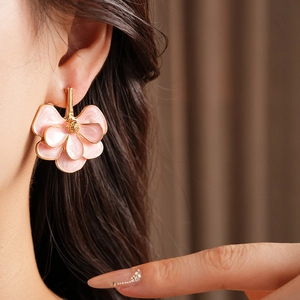 Close-up of pink flower petal earrings with gold finish on model for vintage look