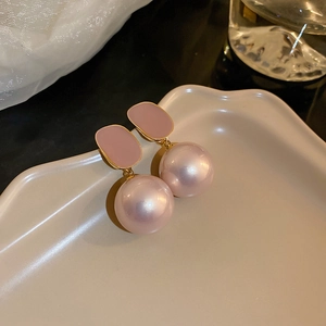 Close-up of vintage geometric earrings with pink enamel and large glossy pearls