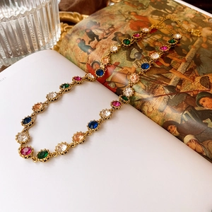 Close-up of vintage baroque necklace with colorful crystals on a retro book background