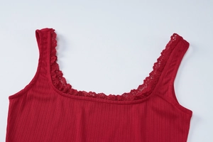 Détail d'un caraco rouge en maille côtelée avec bordure en dentelle sur l'encolure carrée