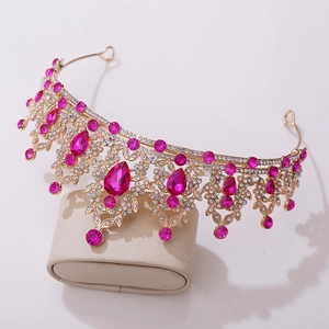 Detail of golden bridal tiara featuring leaf design, clear crystals and pink rhinestones
