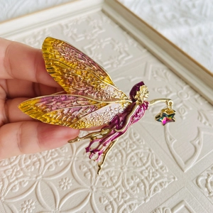 Detail of fairy brooch with colorful enamel wings and a rainbow star charm held in hand