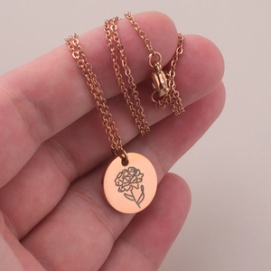 Macro shot of a rose gold necklace featuring a round carnation flower engraved pendant