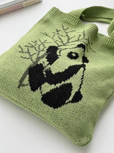 Close-up of cute panda pattern on light green knitted tote bag with textured yarn