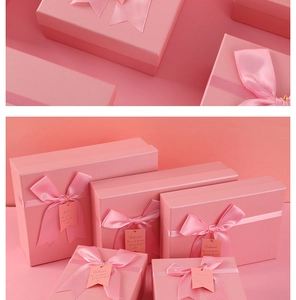 Close-up of pink gift boxes with satin ribbon bows and Beloved tags for wedding favors