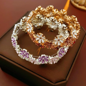 Detail von blumenförmigen elastischen Armbändern in Gold-Weiß und Silber-Lila Emaille