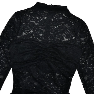 Close-up of black floral lace fabric with long sleeves and elegant mock neckline details