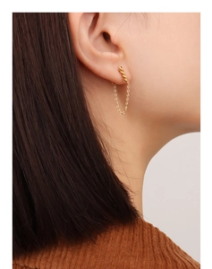 Detail of gold-plated tassel chain earrings showing elegant twist texture on model
