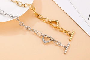Detailed macro of gold and silver heart-shaped toggle clasps and textured chain bracelets