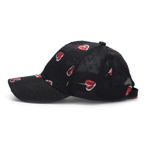 Close-up of distressed black baseball cap with red and white embroidered heart patterns