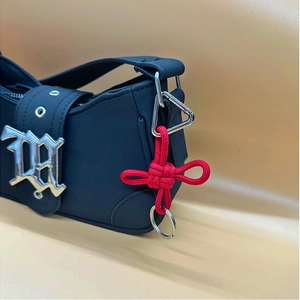 Black matte shoulder bag with silver buckle and decorative red braided keychain cord