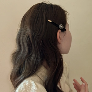 Detail of velvet camellia hair clip worn on side hair for a French vintage elegant look