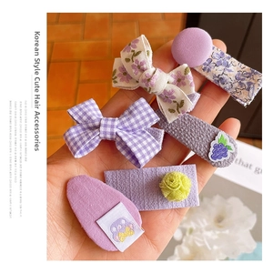 Detail of 5-piece purple hair clip set featuring floral patterns and bow designs