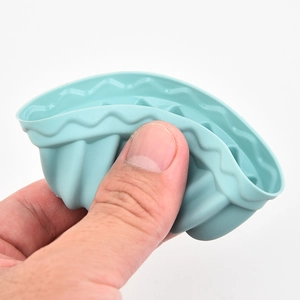 Flexible light blue silicone muffin mold being squeezed to show soft material texture