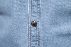 Vue détaillée des coutures d'une chemise en jean avec un bouton métallique embossé