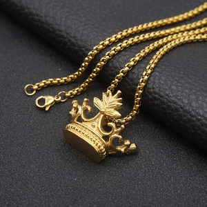 Detailed view of a polished gold crown pendant with a box chain on black leather background