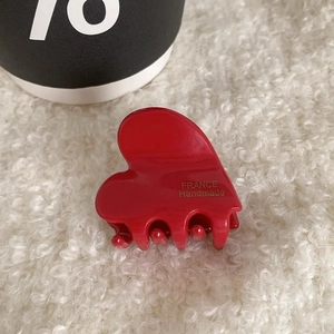 Detailed close-up of a small glossy red heart-shaped hair claw with gold France handmade text