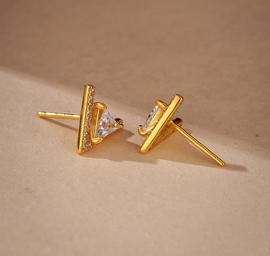 Macro shot of gold triangle stud earrings with white zircon accents and large center stone