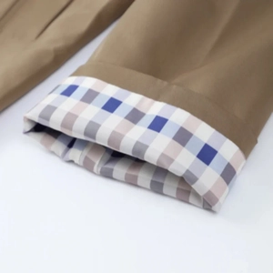 Detailansicht der khakifarbenen Trenchcoat-Manschette mit blau-grauem Karofutter