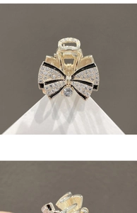 Detail of small metal bow hair claw clip with rhinestones in gold and black finish
