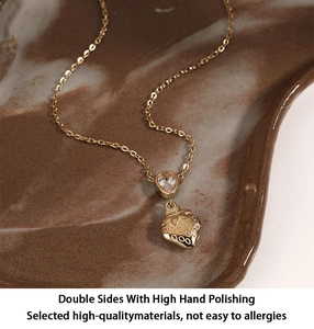 Detail of gold strawberry pendant necklace with a water drop zircon on a textured tray