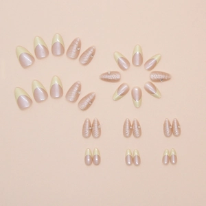 Detailed view of almond French press-on nails with 3D shell lines, yellow tips and rhinestones