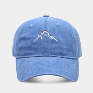 Washed blue cotton baseball cap with mountain and sun embroidery on a grey background