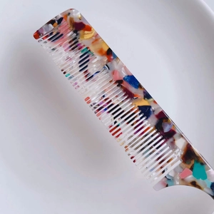 Colorful acetate hair comb with fine teeth and pointed tail on a white background