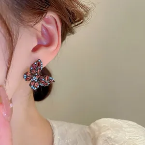 Retro butterfly earrings with red gemstones and blue accents on a silver needle base